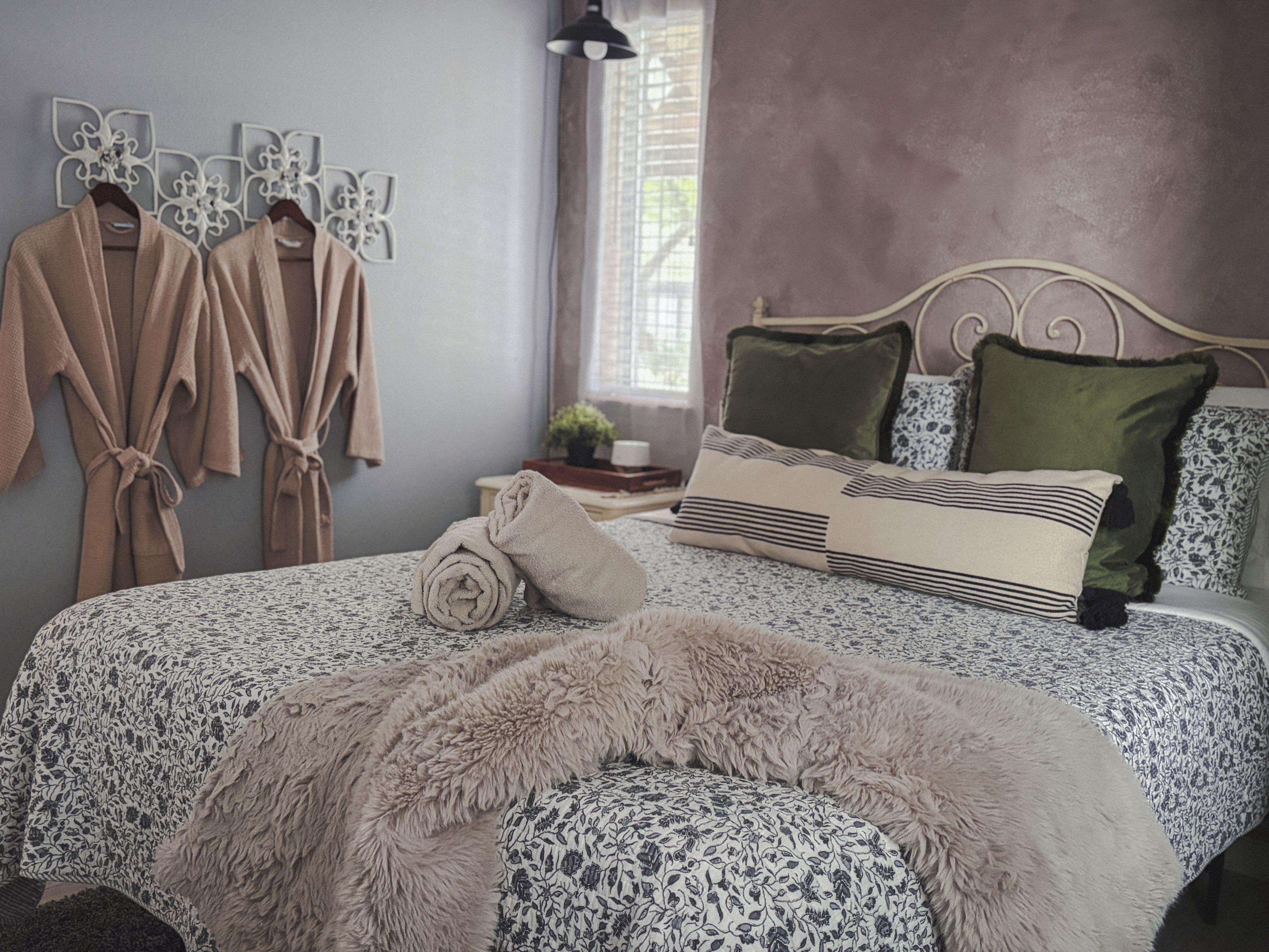 A bedroom with a bed, pillows, a blanket, and a wall-mounted towel rack.