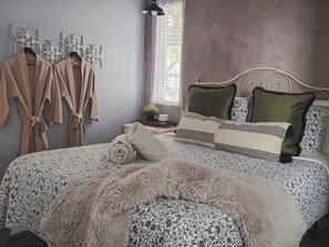 A bedroom with a bed, pillows, a blanket, and a wall-mounted towel rack. - The French Quarters -A Beautiful Boutique 2BR Retreat (Greenwood Village)