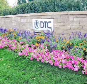 A DTC sign on a stone wall with a flower bed in front. - The French Quarters -A Beautiful Boutique 2BR Retreat (Greenwood Village)