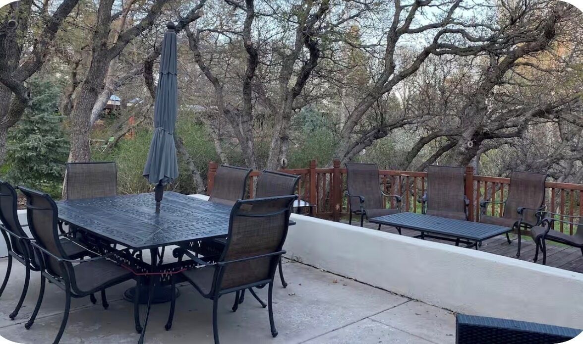An outdoor patio with a table and chairs, a bench, and a wooden fence.