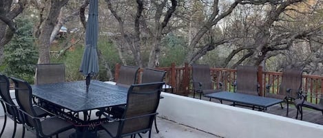 An outdoor patio with a table and chairs, a bench, and a wooden fence.