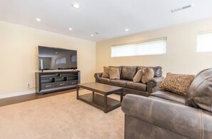 A living room with a sofa, coffee table, TV, and entertainment unit. - Old Broadmoor Retreat with 2 Universal Tesla Chargers - House 5 Bedrooms 9 Beds (Colorado Springs)