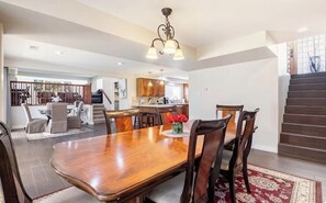 A spacious dining area with a wooden table and chairs, a chandelier, and a view of the kitchen and living area. - Old Broadmoor Retreat with 2 Universal Tesla Chargers - House 5 Bedrooms 9 Beds (Colorado Springs)