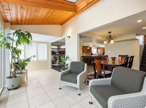 A spacious living area with a high ceiling, a dining table, and two sofas. - Old Broadmoor Retreat with 2 Universal Tesla Chargers - House 5 Bedrooms 9 Beds (Colorado Springs)