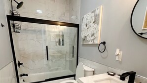 Une salle de bain moderne avec une douche à parois de verre, des toilettes et un meuble-lavabo avec un évier.