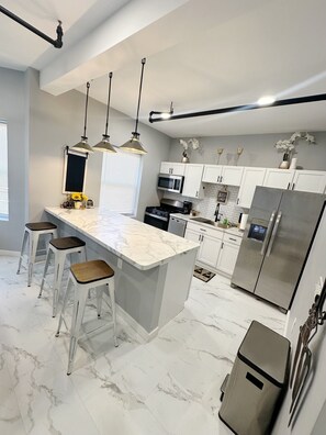 A modern kitchen with a marble countertop, stainless steel appliances, and pendant lighting. - Charming 1bedroom Suite 7minutes from Downtown Cleveland (Cleveland)