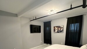 Une chambre avec un grand lit, un téléviseur à écran plat fixé au mur et un luminaire au plafond.