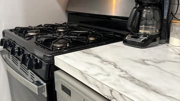 A kitchen with a stainless steel stove, a dishwasher, and a coffee maker on the countertop.