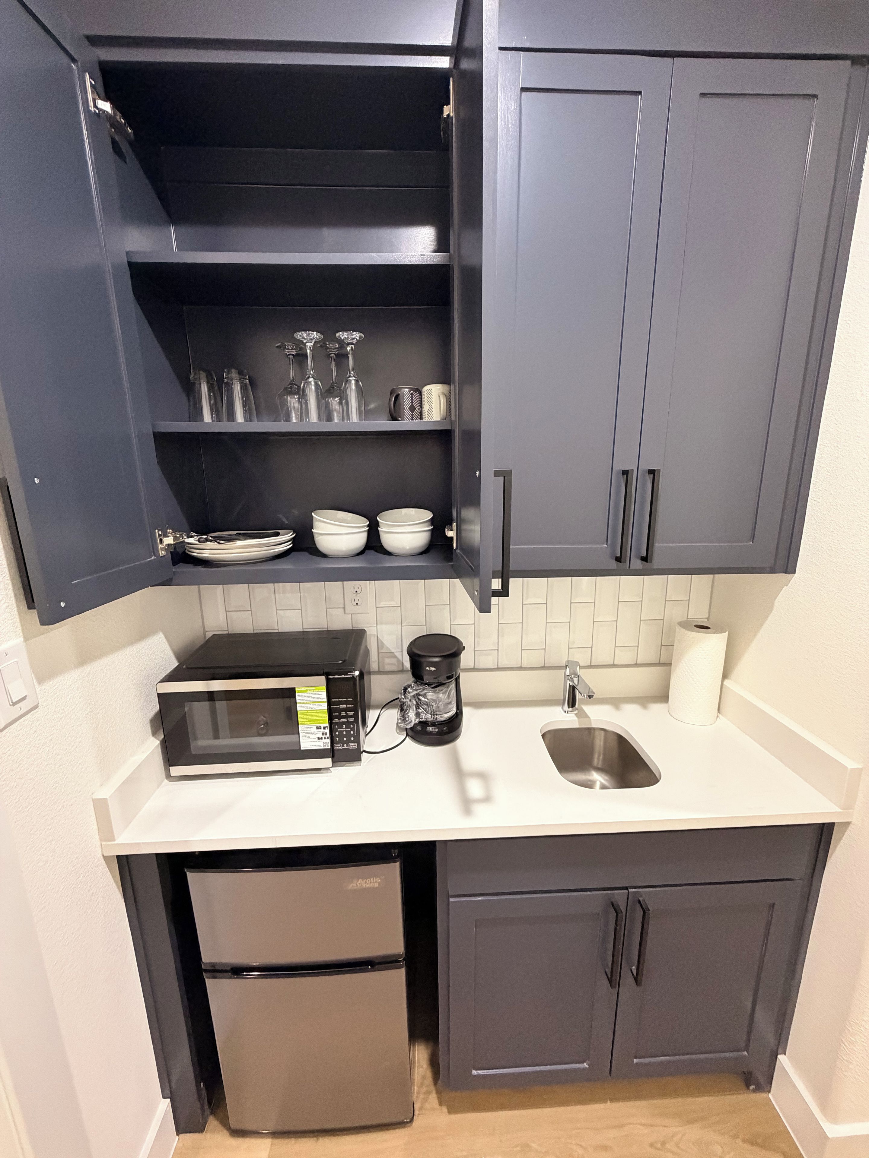 A compact kitchen with a microwave, coffee maker, and a refrigerator.