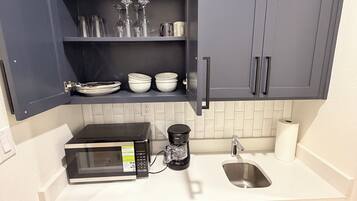A compact kitchen with a microwave, coffee maker, and a refrigerator.