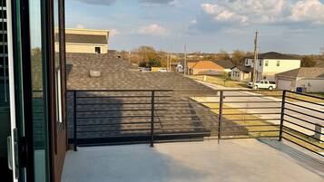 A balcony with a view of a residential neighborhood, including houses and a parking area.