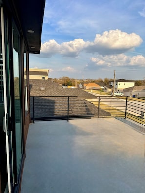 A balcony with a view of a residential neighborhood, including houses and a parking area.