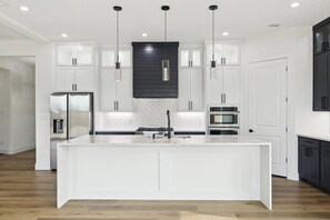 A modern kitchen with white cabinetry, a central island, and pendant lighting.