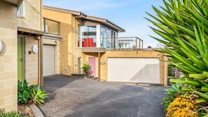 Een woonhuis met twee verdiepingen, een garage, een balkon en een oprit.