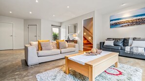 Een moderne woonkamer met een bank, een salontafel en een trap naar een hoger gelegen verdieping.