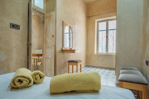Een kamer met een bed, een bankje, een raam en een spiegel.