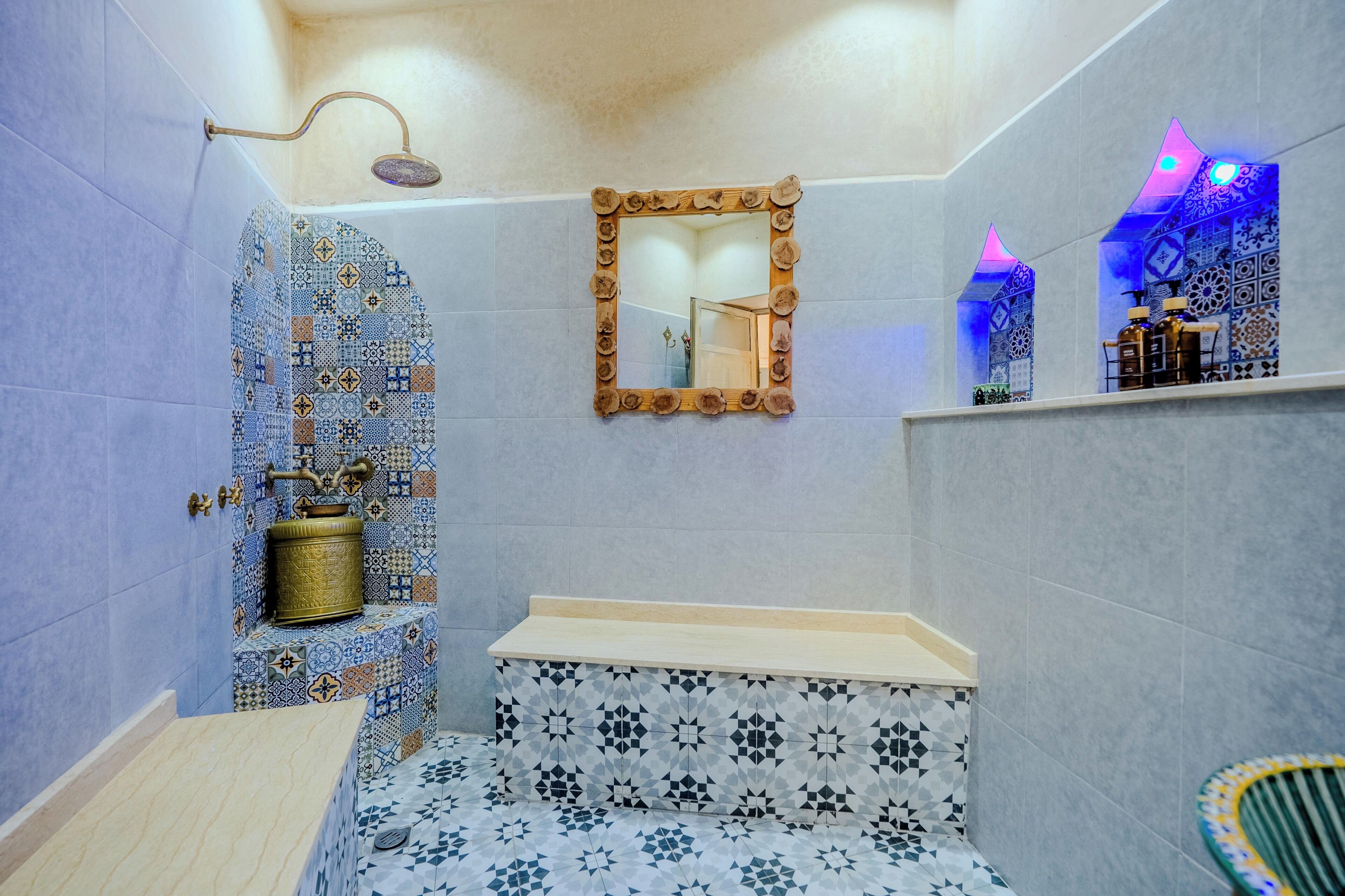 Un baño con lavamanos, espejo, ducha y azulejos decorativos.
