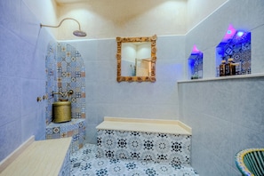 Een badkamer met een wastafel, spiegel, douche en decoratieve tegels.