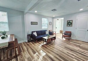 A living room with a dark blue sofa, a wooden coffee table, and a patterned armchair. - Cozy 2-bedroom condo with AC in amazing Miami location (Miami)