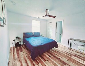 A bedroom with a bed, a nightstand, a desk, a ceiling fan, and a door. - Cozy 2-bedroom condo with AC in amazing Miami location (Miami)
