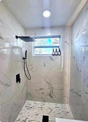 A modern bathroom with a shower, a window, and a shelf with toiletries. - Cozy 2-bedroom condo with AC in amazing Miami location (Miami)
