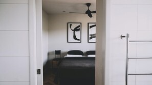 A bedroom with a bed, a ceiling fan, and two abstract wall art pieces. - Elevation - 1 Bedroom (Bright)