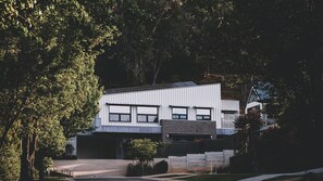 A modern two-story house with a garage, surrounded by trees. - Elevation - 1 Bedroom (Bright)