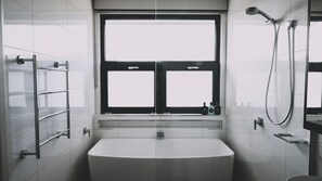 Une salle de bain moderne avec une grande fenêtre, une baignoire et une douche.