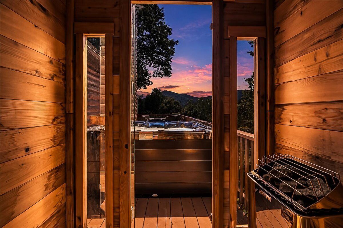 A wooden cabin with a hot tub and a grill outside.