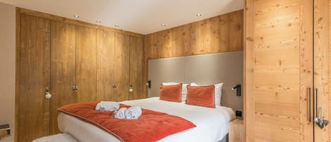A bedroom with a large bed, wooden wardrobe, and a headboard.