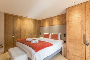 Un dormitorio con una cama grande, un armario de madera y un cabecero.