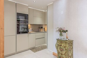 Eine moderne Küche mit integrierten Geräten, einem kleinen Beistelltisch mit einer Vase und einer Wand mit Muster.