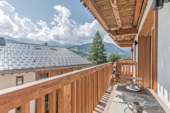 Un balcón de madera con vistas a montañas y un cielo despejado.
