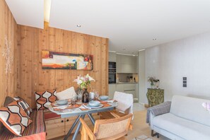 Ein modernes Wohnzimmer mit Essbereich, Holzwandverkleidung und einer Küche im Hintergrund.