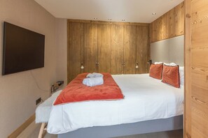 Ein Schlafzimmer mit einem Bett, einem Holzschrank, einem Flachbildfernseher und einem kleinen Nachttisch.