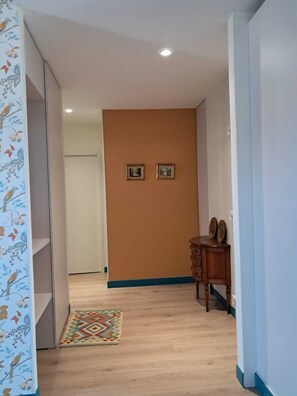 Un pasillo con alfombra estampada, muebles de madera y dos cuadros en la pared.