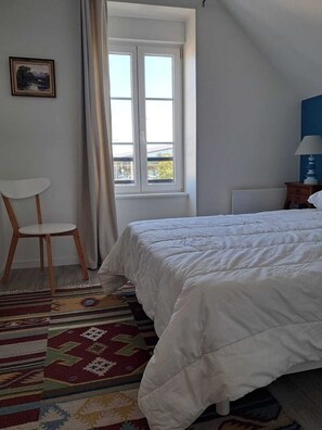 Ein Schlafzimmer mit einem Bett, einem Sessel, einem Fenster und einer Lampe.
