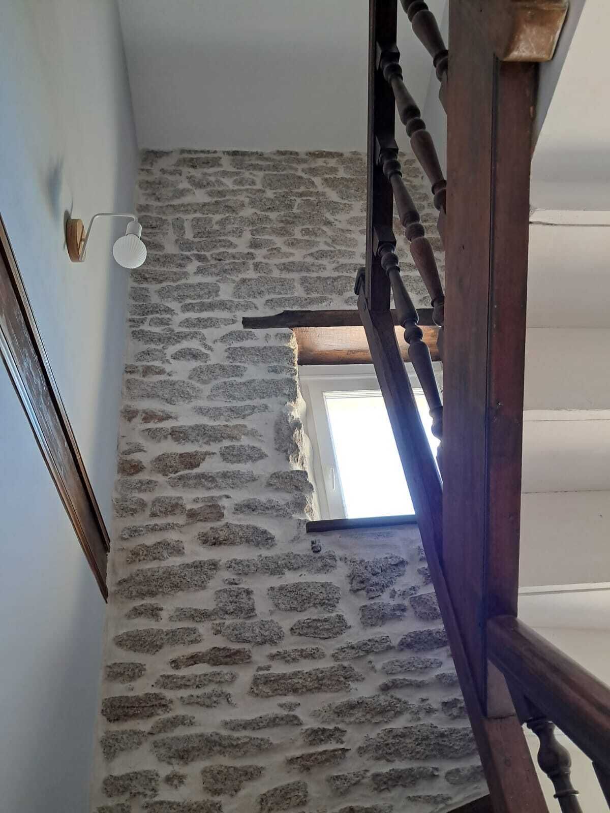 A staircase with a stone wall and a wooden handrail.