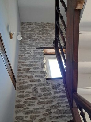 A staircase with a stone wall and a wooden handrail. - Cozy apartment in the heart of the Bigouden region, close to the beaches and shops (Plomeur)