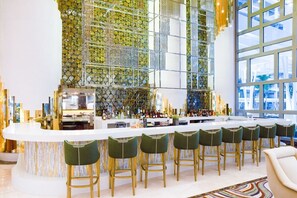A bar area with a white countertop, green bar stools, and a decorative glass wall. - Spend Christmas week in luxury at 5-star Garza Blanca Cancún! (Cancún)