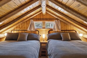 A cozy attic bedroom with two beds, wooden beams, and a window. - Yellowstone ; Fly Fishing ; Trail Riding ; Snowmobiling (Island Park)