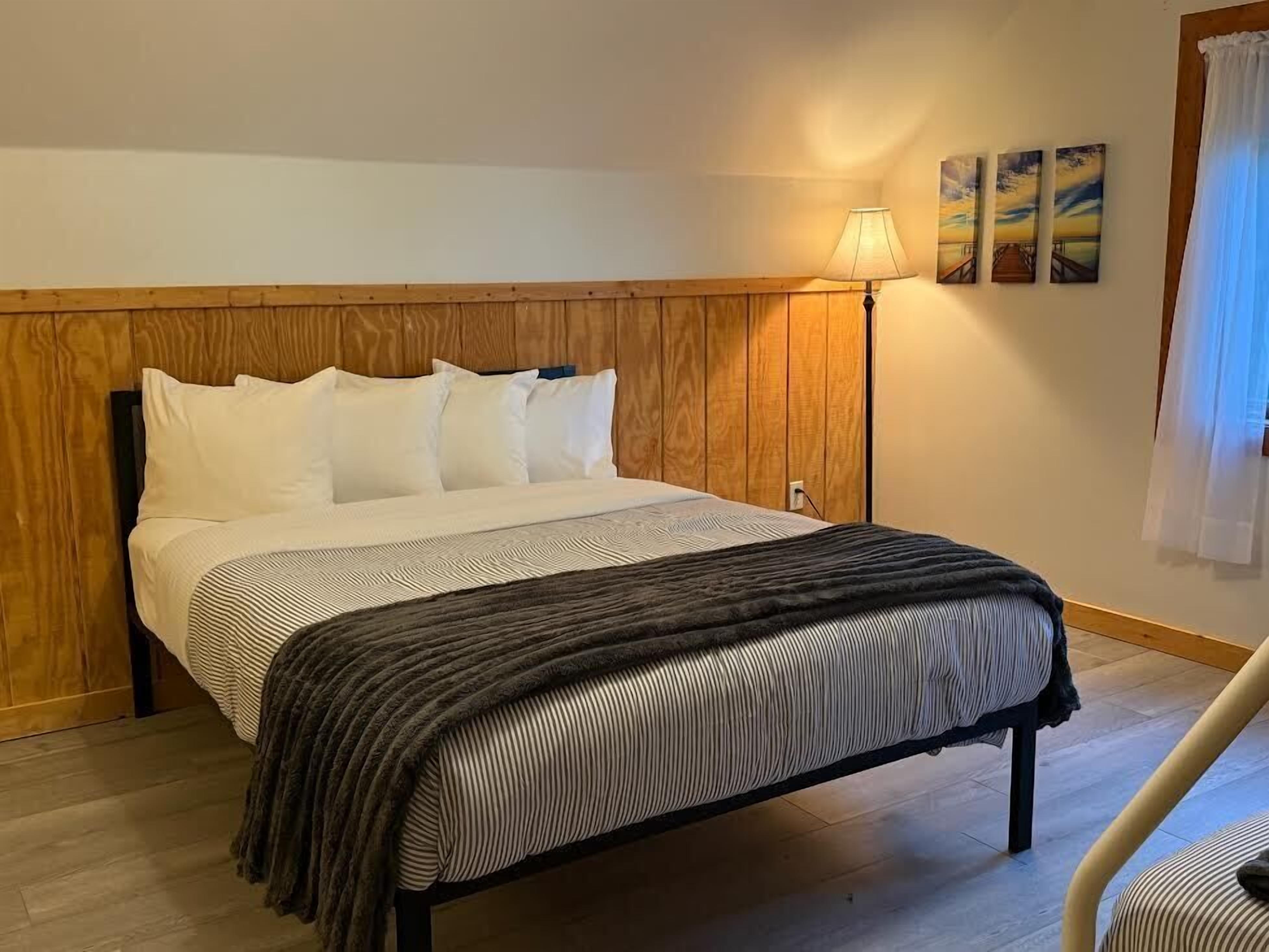 A bed with a wooden headboard, a bedside lamp, and a view of the room's interior.