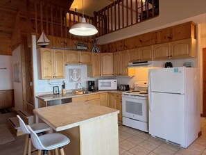 Una cucina con mobili in legno, un frigorifero bianco, un forno a microonde e un fornello.