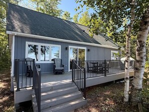 A two-story house with a covered porch, outdoor seating, and a small deck. - Crane Cabin-Set directly along the sandy shores of Amnicon Bay, Aajijash (La Pointe)