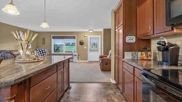 A kitchen with wooden cabinets, a granite countertop, and a stainless steel range hood.