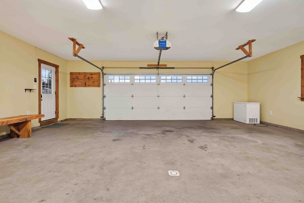 A garage with a white door, a ceiling-mounted projector, and a wooden bench.