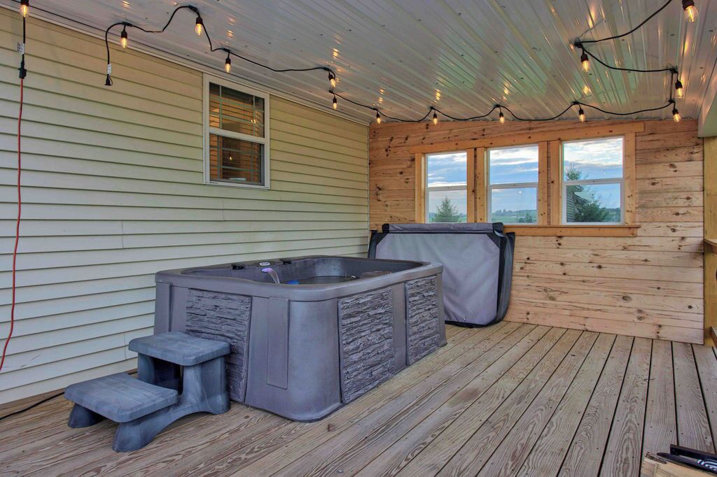 Un jacuzzi en una terraza de madera con luces colgantes.