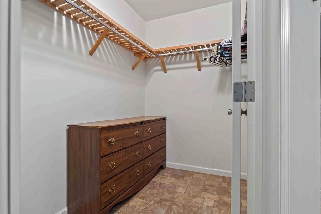 Ein Zimmer mit einem Holzkleiderschrank, einem Kleiderständer und einer Tür mit Griff.