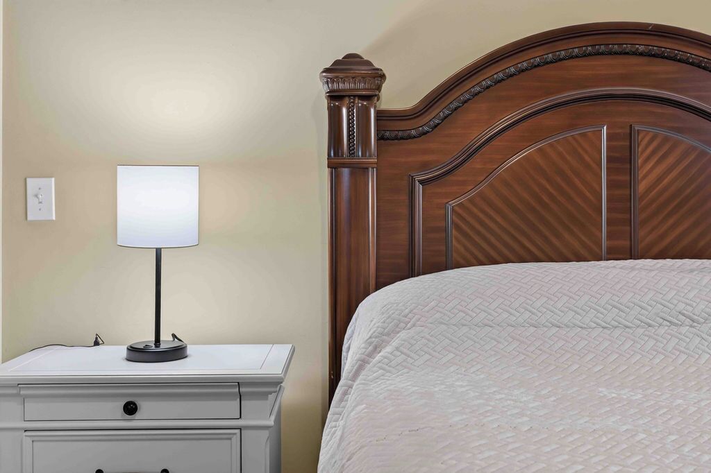 Un lit bien fait, avec une couverture matelassée, une table de chevet avec une lampe et une tête de lit en bois.
