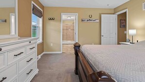 Un dormitorio con una cama grande, un aparador, una puerta y un pasillo que conduce a otra habitación.